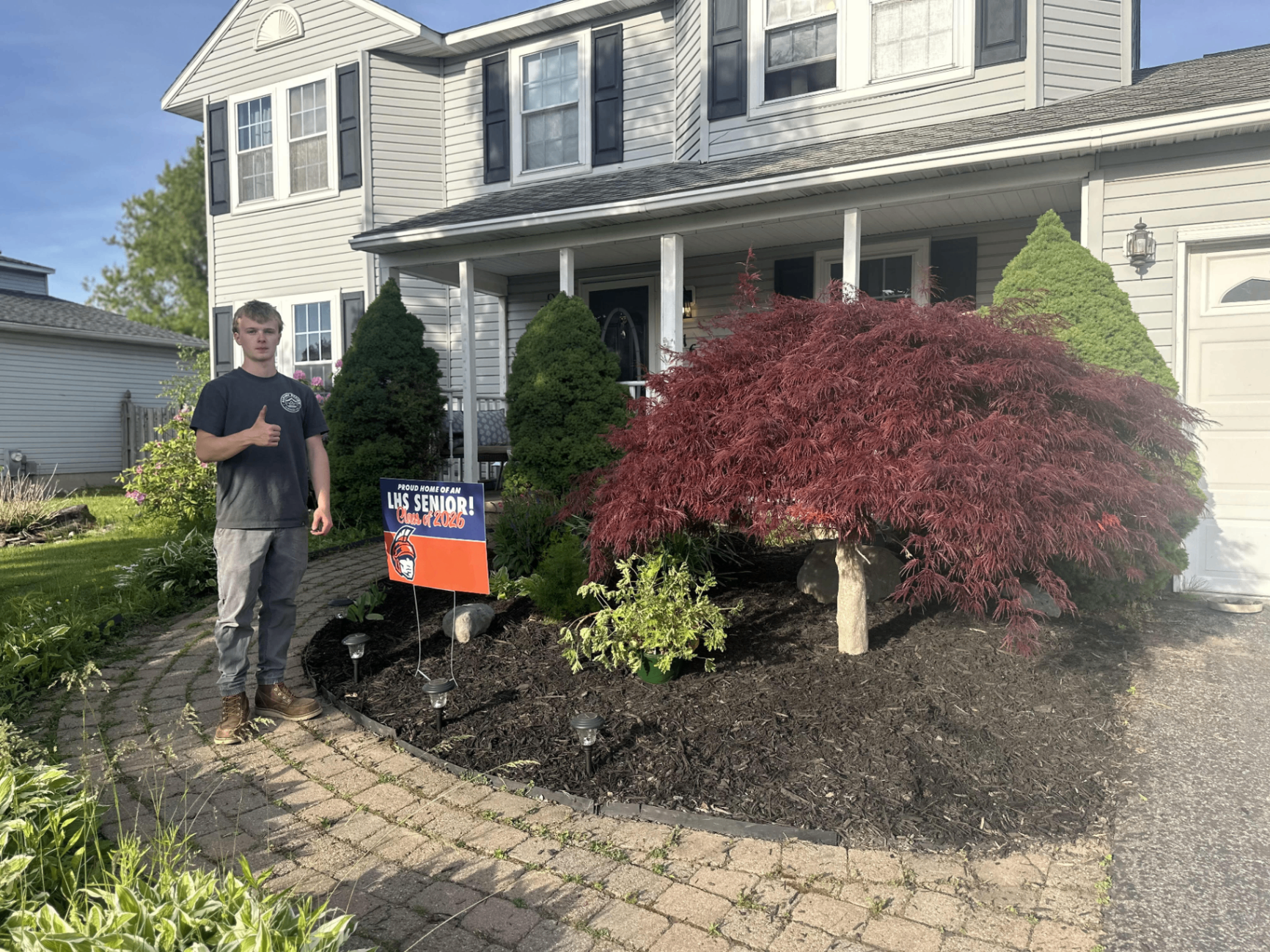 Season Shift LLC crew member in front of a freshly mulched landscape bed with Japanese maple